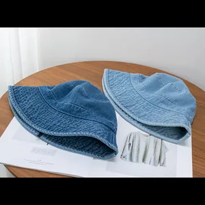 Detail of blue denim bucket hats with reinforced stitching on a wooden table