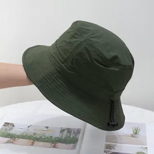 Close-up of quick-dry green bucket hat with adjustable black drawstring and reinforced brim