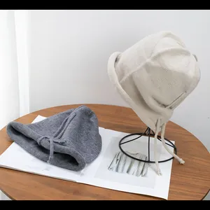 Detailed knit texture and rolled edge on gray and beige drawstring beanies
