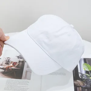 Detail of a white cotton baseball cap showing the curved brim and reinforced stitching