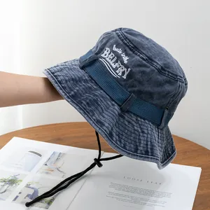 Detail of washed blue cotton bucket hat featuring white embroidery and adjustable chin strap