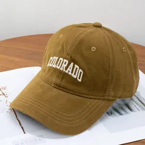 Macro shot of white Colorado embroidery on mustard yellow cotton baseball cap