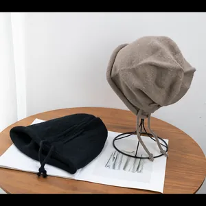 Detail of black and brown knit slouchy beanies with drawstring on a wooden table