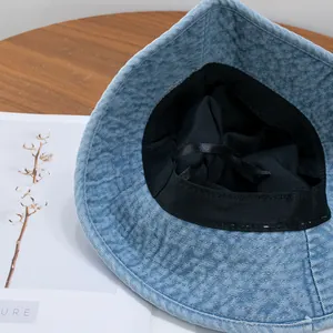 Blue denim bucket hat with internal black lining and adjustable drawstring on wood table