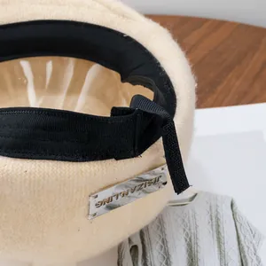 Beige knitted wool newsboy beret hat for women with elegant silver metal logo plate