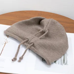 Detailed texture of light brown knitted beanie with drawstring ties and rolled edges