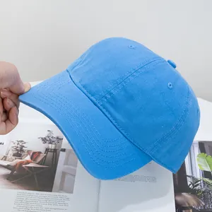 Detail of bright blue washed cotton baseball cap held by hand featuring breathable eyelets