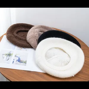 Close-up of four knitted mohair berets in brown and beige tones on a wooden table
