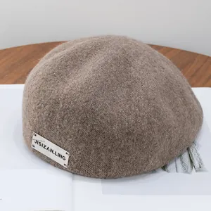 Detail view of coffee brown wool newsboy cap showing fuzzy texture and decorative label