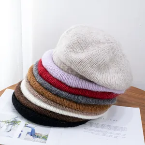 Close-up of soft mohair knit berets stacked in multiple colors on a wooden table