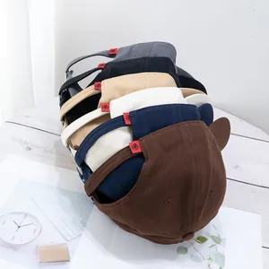 Close-up of stacked cotton baseball caps with embroidered red tags and cute ear details