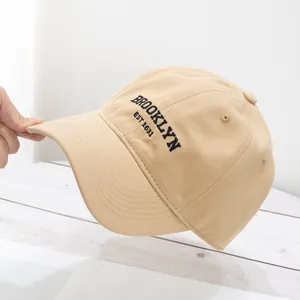 Detail of Brooklyn embroidery on khaki cotton baseball cap with hand showing fabric texture