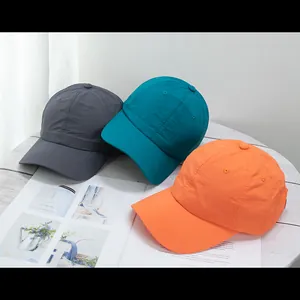 Flat lay of lightweight quick-dry baseball caps in grey, blue, and orange on wood table