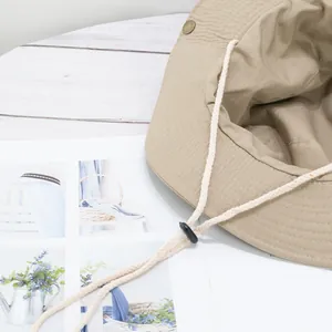 Khaki outdoor sun hat with adjustable windproof rope on a light wood background