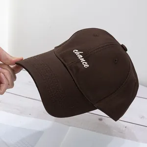 Detalle de una gorra de béisbol de algodón marrón oscuro con bordado blanco de chance