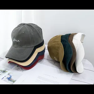 Variety of cotton baseball caps with 'me' embroidery shown on a wooden background