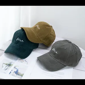 Detailed embroidery of lowercase 'me' on vintage canvas baseball caps in earth tones