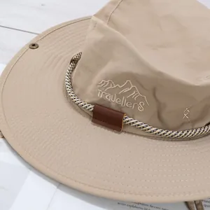 Close-up of beige sun hat with mountain embroidery, wide brim and adjustable wind cord
