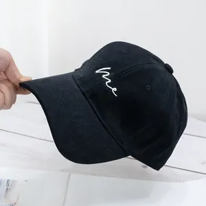 Detail of black cotton baseball cap showing white me embroidery and textured twill fabric