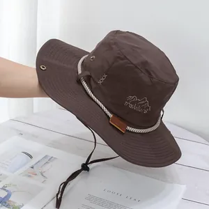 Detail of dark brown outdoor hat featuring traveler embroidery and windproof chin strap