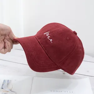 Close-up of burgundy cotton baseball cap with white Me embroidery on wooden background