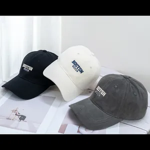Three embroidered cotton baseball caps in black, off-white, and grey colors shown on desk
