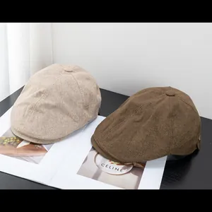 Berretti newsboy retrò in lino beige e marrone esposti su una rivista di moda