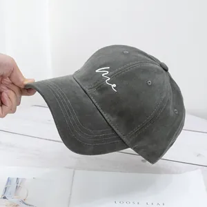 Detailed view of dark gray cotton baseball cap with white me embroidered script