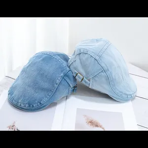 Detail of adjustable metal buckles on vintage denim flat caps in blue and light blue