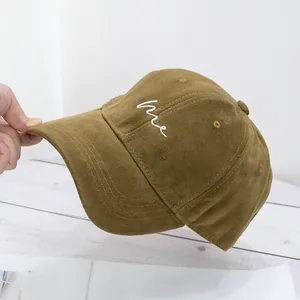 Detail shot of a mustard cotton baseball cap with white me letter embroidery