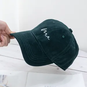 Macro detail of dark green cotton baseball cap featuring white 'me' script embroidery