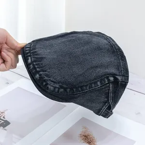 Close-up of black denim flat cap showing washed texture and side adjustment buckle
