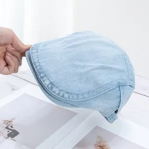 Detail view of light blue denim flat cap showing premium stitching and fabric texture