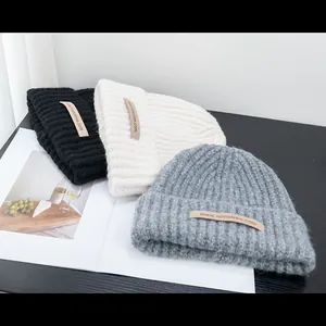 Winter chunky knit wool blend beanies in black, beige, and grey with woven patch labels