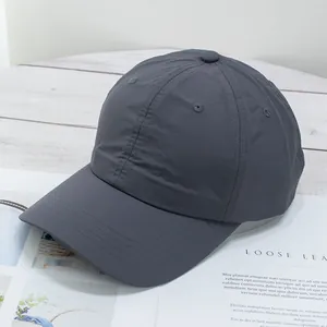 Detail view of a dark grey lightweight baseball cap on a stylish magazine background