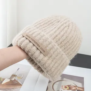 Close-up of beige ribbed knit beanie featuring thick texture and branded woven label