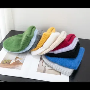 Berretti in maglia morbida in vari colori vivaci disposti su una rivista di moda