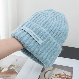 Detail of light blue knit beanie showing soft wool blend texture and rectangular woven label