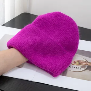 Dettaglio di un berretto in maglia magenta con soffice trama in pelo di coniglio su nero