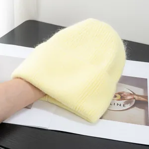 Dettaglio del berretto in maglia color crema con trama a costine e finitura in pelo