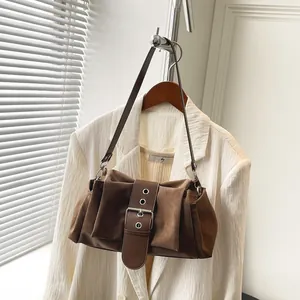 Retro brown faux suede shoulder bag with large decorative belt buckle and silver eyelets