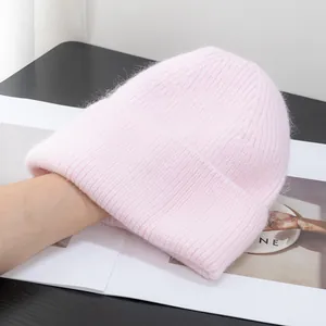 Dettaglio del berretto in maglia rosa morbido con texture pelosa e bordo risvoltato