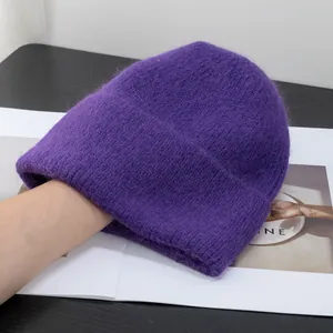 Dettaglio del cappello in maglia viola scuro che mostra la morbida trama in finta pelliccia