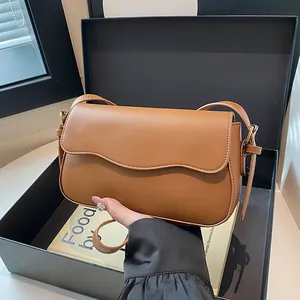 Elegant brown leather crossbody bag with wave-edge flap and gold metal hardware