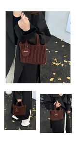 Detail der Strickstruktur einer braunen Häkeltasche mit Herzanhänger
