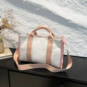 Minimalist cream canvas tote bag with pink straps on a textured stone background