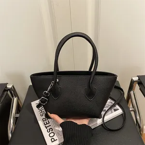 Minimalist black pebbled leather bucket bag with silver hardware and dual carry straps