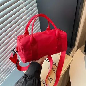 Minimalist red cylindrical tote bag with adjustable shoulder strap for fitness travel