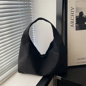 Minimalist black faux suede half-moon shoulder bag in a modern aesthetic setting
