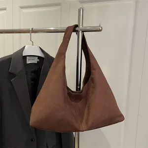 Minimalist dark brown faux suede tote bag on metal rack against a grey blazer